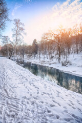 Fototapeta premium Breathtaking landscape in city park with snowy trees and beautiful reflection in frozen river.