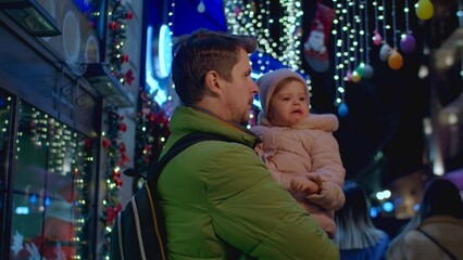 Man with crying daughter at street with Christmas lights and decoration, waiting for mother 