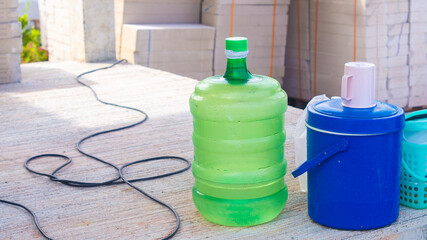 Green plastic bucket for drinking water with a blue flask and glass at the top. of workers working in construction