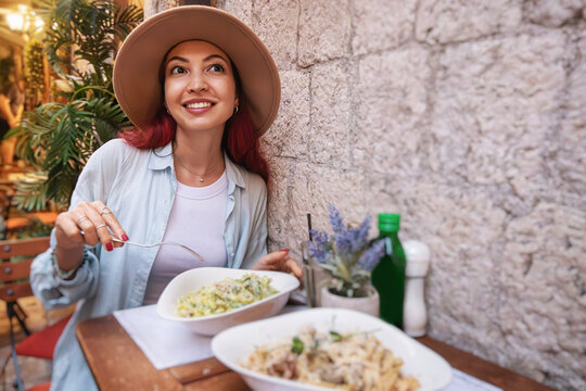 Fototapeta Young woman eating pasta in a typical Italian restaurant, savoring local cuisine during her travel