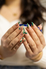 Female hands with green and gold nail designs. hands holding blue and white coffee cup