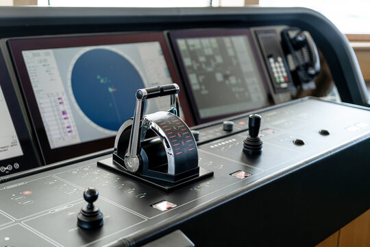 Detail shot of the throttle controls, radar and ship's systems in the bridge of a modern superyacht, with dark leather interior
