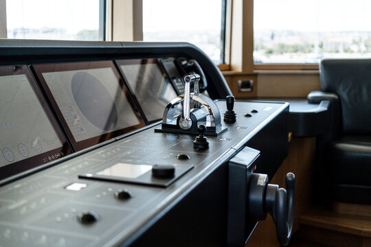 Detail shot of the throttle controls, radar and ship's systems in the bridge of a modern superyacht, with dark leather interior
