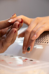 A professional nail technician makes Christmas nail designs in a beauty salon. Woman hands with Christmas tree and candy cane design. Merry Christmas. Candy cane nails. Snowflake nails. Winter nails.