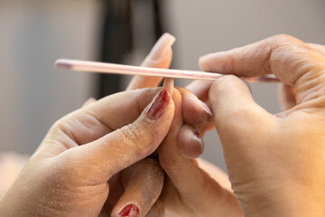 A professional nail technician creates nail designs on women's hands in a beauty salon. Equipment used in manual nail design