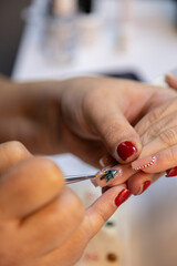 A professional nail technician makes Christmas nail designs in a beauty salon. Woman hands with Christmas tree and candy cane design. Merry Christmas. Candy cane nails. Snowflake nails. Winter nails.