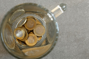 gold coins in a glass jar on a gray surface