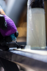 Close-up shot of a tattoo artist using a tattoo machine to create a detailed design on a client’s arm, with a focus on the purple stencil and black gloves. Perfect for tattoo art, creativity, and life