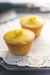A beautifully arranged plate of lemon tarts, showcasing their vibrant yellow filling and delicate pastry crust, invites you to indulge in a delightful culinary experience. The smooth lemon curd