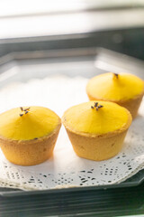A beautifully arranged plate of lemon tarts, showcasing their vibrant yellow filling and delicate pastry crust, invites you to indulge in a delightful culinary experience. The smooth lemon curd