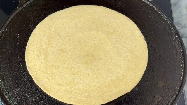 Crispy Paratha on black pan with bubbles. Cooking paratha in butter on a black Tawa with bubbles on it. Butter paratha with bubbles and smoke. 