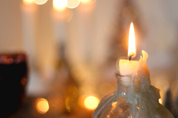 Various Christmas decorations, cookies, chocolate, nuts and tangerines, wine glasses and lit candles on the table. Holiday hygge at home. Selective focus.