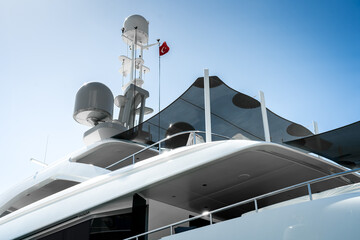 Naklejka premium Detail of stern and antennas of a spotless modern superyacht at dock in Gocek marina in Turkey, with blue sky