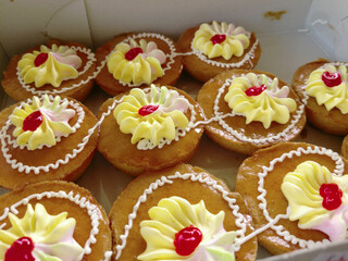 Mini cakes coated with caramel and piped with whipped cream.