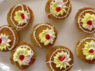 Mini cakes coated with caramel and piped with whipped cream.
