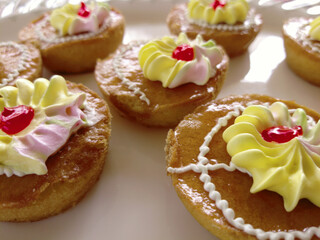 Mini cakes coated with caramel and piped with whipped cream.