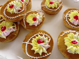 Mini cakes coated with caramel and piped with whipped cream.