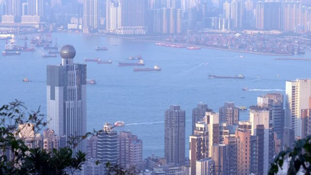 Buildings stand against the water during the daytime in Hong Kong with a view of the big ships