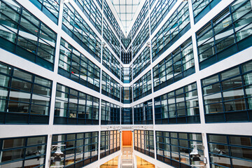 Modern Office Building Interior With Symmetrical Glass Windows and Bright Architecture Featuring a Staircase at the Core, Creating a Futuristic Perspective in a Contemporary Urban Work Environment