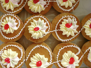 Mini cakes coated with caramel and piped with whipped cream.