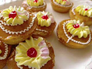 Mini cakes coated with caramel and piped with whipped cream.