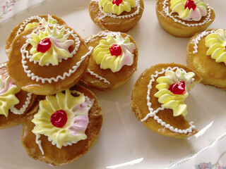 Mini cakes coated with caramel and piped with whipped cream.