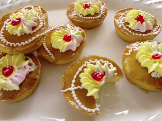Mini cakes coated with caramel and piped with whipped cream.