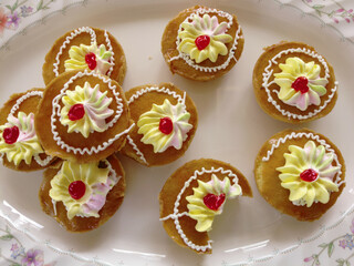 Mini cakes coated with caramel and piped with whipped cream.