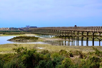 The long wooden bridge leads over the arms of the Ria Formosa Lagoon to the beach, which is located on a peninsula of the coast. Quinta do Lago, Almancil, Algarve, Portugal