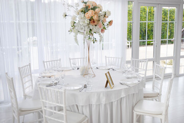 white chairs with tablecloth and floral decoration at banquet