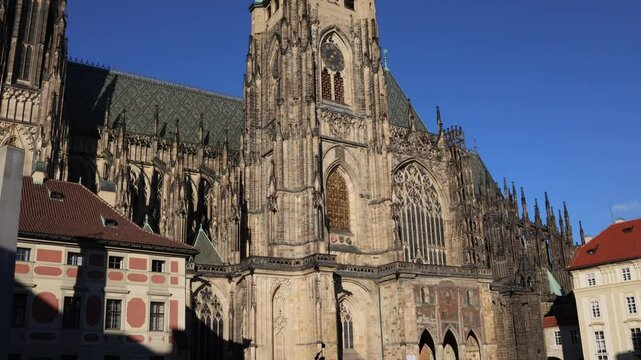 A majestic Gothic cathedral under a clear blue sky, showcasing intricate architectural details and a prominent clock tower. The scene exudes historical grandeur and timeless beauty.
