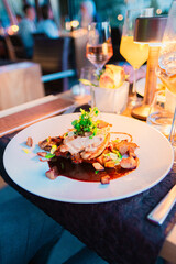 Gourmet Dinner Setting Featuring A Deliciously Plated Chicken Dish With Artful Presentation Surrounded By Warm Ambient Lighting And Tall Elegant Wine Glasses In A Sophisticated Restaurant Atmosphere