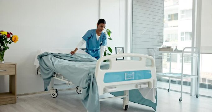 Healthcare, caregiver and preparing of hospital room, woman and making of bed, service and fresh blanket. Serious, medical professional and cleaning of nursing home, nurse and person with sheets