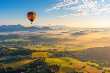 Obraz premium Hot air balloons float over a scenic landscape with mountains and valleys during sunrise