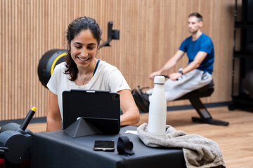 Brunette woman in gym looking a tablet