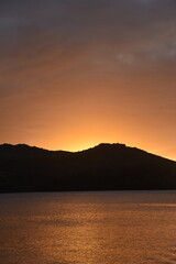 Stunning Pacific Ocean sunset with beams of colourful light shining up from the sea and islands in Fiji