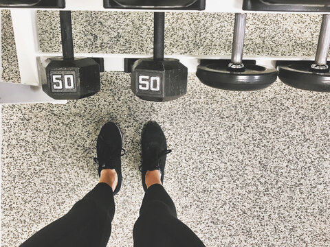 Overhead view of a woman standing by rack of dumbbells in a gym