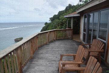A wooden porch / balcony in a tropical cabin overlooking the turquoise Pacific Ocean and corals in Tonga