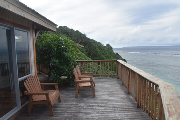 A wooden porch / balcony in a tropical cabin overlooking the turquoise Pacific Ocean and corals in Tonga