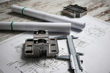 Metal machined parts lying on a technical drawing with a caliper, showcasing precision engineering...