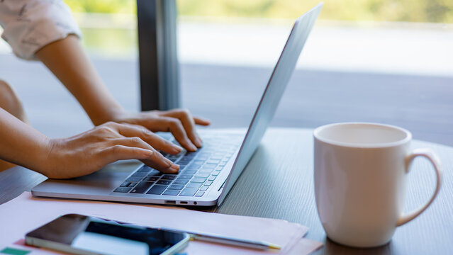 Female hands typing on laptop computer keyboard on wood desk at office, Technology, Business concept. Business woman analyze the graph of the company performance to create profits and growth.