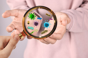 Woman looking at man's hand with magnifying glass, closeup. Illustration of microbes