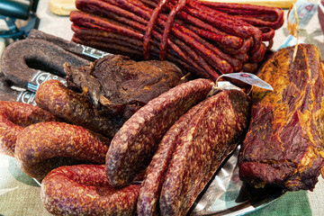Various delicious jerky gammon and sausages on dish, top view. Traditional ready-to-eat meat products on the counter in the market.