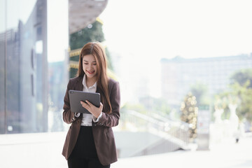 Confident businesswoman walks down a lively city street with laptop in hand. She exudes determination and success.