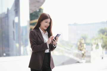 Confident Asian businesswoman standing on a busy city street with a smartphone in her hand, stylish and professional, representing the modern entrepreneur.