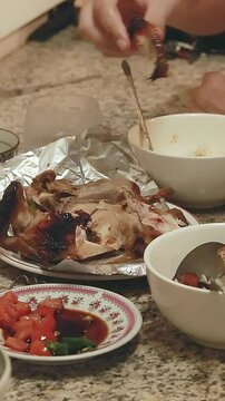 Eating lechon manok or roasted chicken with bare hands that shows a candid and authentic Filipino cultural cuisine