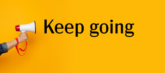 Hand with a megaphone and a keep going motivational text	