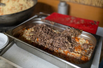 Pilaf with meat is being portioned into containers on a military base.