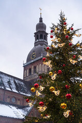Vertical view of the Christmas tree decorated with red balloons and the Riga cathedral on the background. Latvia