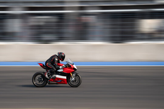Motorcycle rider riding on a red sport bike through the corner at high speed.